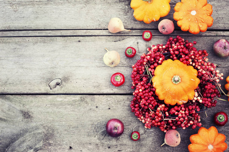 木桌上有南瓜和红色浆果的秋色背景