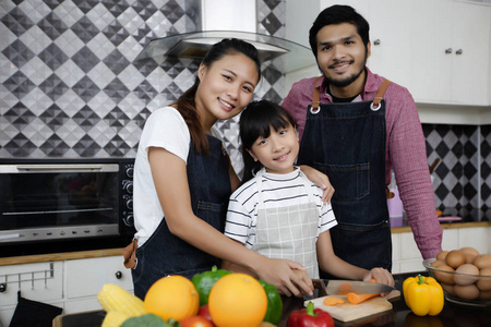 幸福的家庭有爸爸妈妈和他们的小女儿一起在厨房做饭