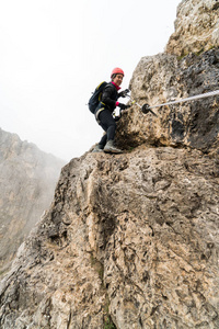 年轻迷人的女登山者，在陡峭的陡峭和暴露通过费拉塔在阿尔塔巴迪亚在意大利白云岩的南部蒂罗尔