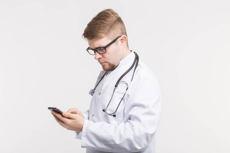健康和医学医生戴听诊器, 看着手机屏幕上的白色背景