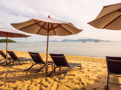 太阳升起时在热带海滩海洋和海洋上的雨伞和椅子，供旅行和度假用