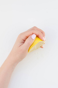 女人手与糊状指甲油，持有一半柠檬隔离在白色背景复制空间极简主义风格。 女性社交媒体模板。 健康饮食观念