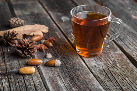 木桌上放着一杯茶橡木叶松果和橡子的秋天背景概念