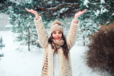 快乐的女人在白雪皑皑的冬林里散步，在雪花上捕捉。 户外季节性活动的概念