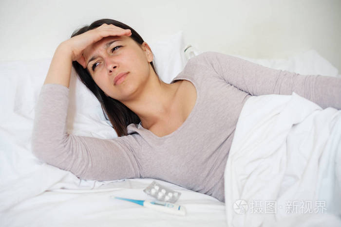 生病的女人在床上感到头痛