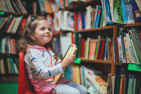 可爱的女孩在图书馆看书。