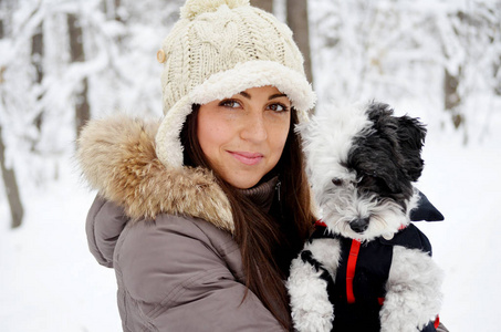 美丽的微笑的女人在冬天和她的Havanese狗在户外玩耍。主人和狗在一起快乐
