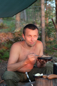 在森林营地吃晚饭欣赏日落的男人