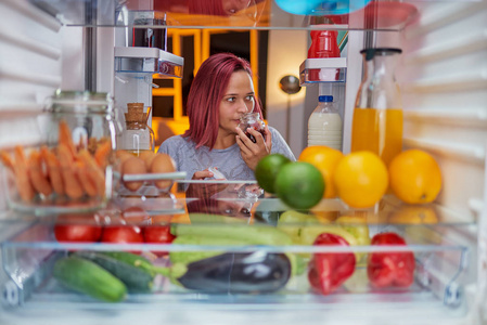 女人在深夜找东西吃。 从冰箱里拍的照片。
