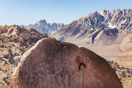 男子岩石爬上巨大的花岗岩巨石在布特米尔克地区的主教加利福尼亚和内华达山脉后面