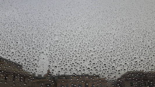 一场春雨过后，从热那瓦市的窗户上流出的水滴的美丽的字幕