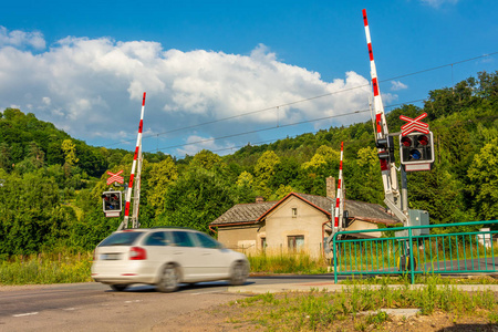 一辆白色客车穿过一个有障碍的铁路道口。在铁路道口前面的信号灯。捷克共和国铁路上的警告信号。到达铁路道口的汽车