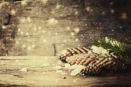 雪中松果的特写镜头，木质背景上的圣诞装饰