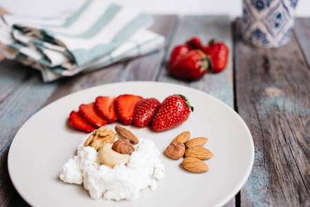 在木桌上放一盘奶酪草莓和坚果一杯咖啡和毛巾健康食品早餐