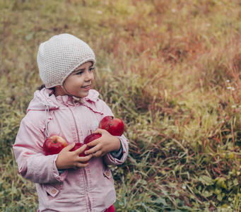 快乐的孩子手里拿着红苹果。秋季公园户外收获有趣的孩子