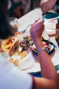 年轻女子在一家街头餐馆准备和吃墨西哥菜。 墨西哥玉米饼，玉米片和翅膀。