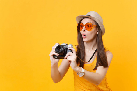游客女士在夏季休闲服装帽子拍照复古老式照片相机隔离在黄色背景。 周末出国旅行的女孩度假。 航空飞行旅程概念