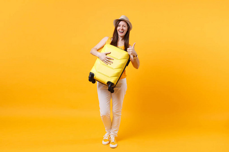 旅行者旅游妇女在夏季休闲服装帽子与手提箱隔离在黄色橙色背景。 女乘客在周末出国旅行，度假。 航空飞行旅程概念