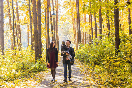 家庭, 秋天, 人的概念青年家庭在秋季公园散步, 拥抱和微笑