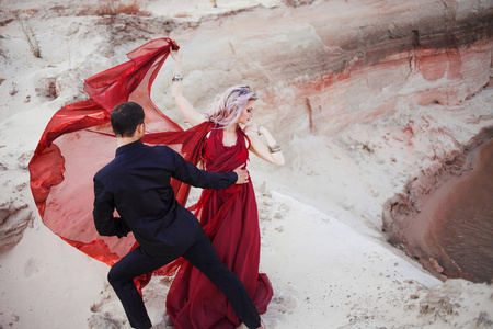 爱和激情, 概念。美丽的年轻夫妇在沙漠中跳舞。黑色的男人和红色的女人