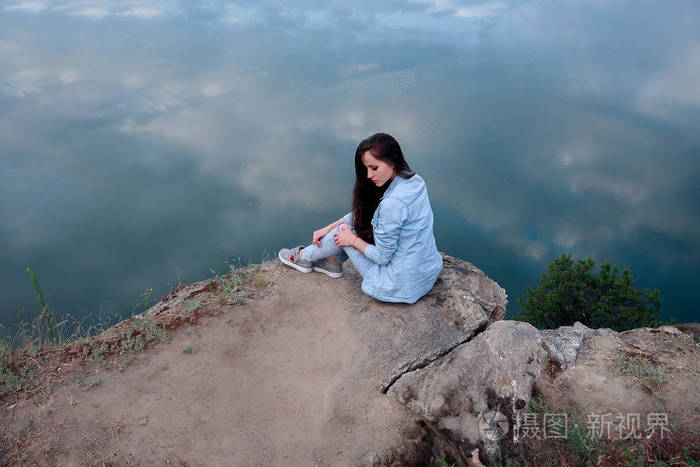 年轻的旅游妇女坐在山顶上,看着一幅美丽的风景. 徒步