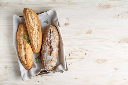 各种自制面包与迷迭香在乡村木箱，顶部视图。酸面包迷你面包小麦和黑麦面包。