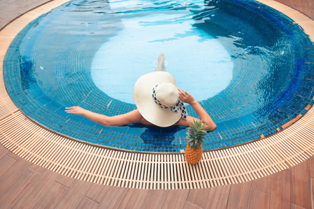 一位亚洲妇女在水疗度假胜地游泳池的暑假肖像。