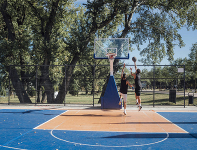 两名年轻球员在户外球场打篮球。