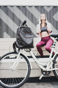 皮革棕色袋在焦点。的年轻女人，背包和老式自行车在城市停车场。自然色彩调色设计。生活方式运动康普特。图片