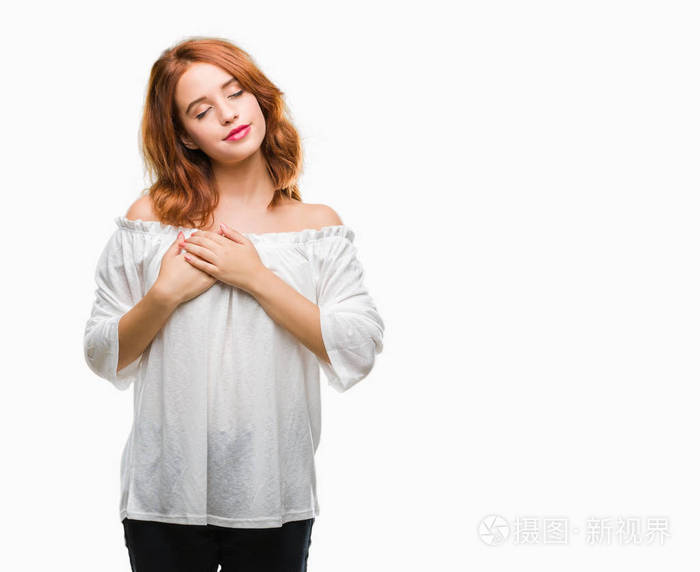 年轻的美女在孤立的背景上微笑双手放在胸部闭着眼睛脸上有感激的手势