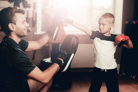 父子拳击训练在健身房。 亲子关系。 运动的家庭概念。 积极的生活方式。 戴拳击手套的孩子。 假日休闲。 一起锻炼。 健身日。