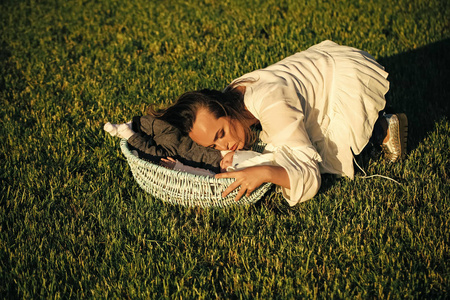 母亲抱着小男孩睡在婴儿床上的绿草