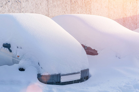 一排停着的车在阳光下覆盖着雪图片