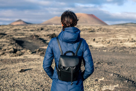 站在蒂曼法亚国家公园兰扎罗特独特火山景观背景下的旅行者女性的后景。 加那利岛的冬天。