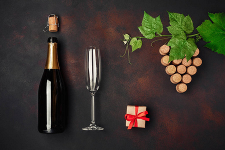 一瓶香槟，葡萄，一束软木，叶子，酒杯礼盒，生锈的背景顶部视图。