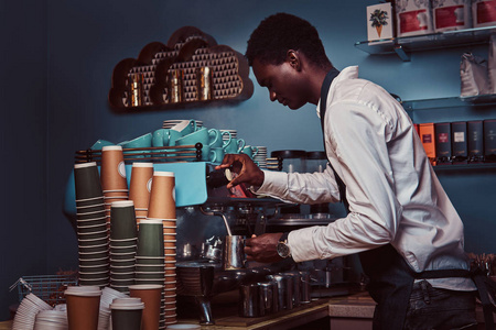 在白色衬衫和围裙的非洲裔美国咖啡师的侧面视图制作咖啡与咖啡机
