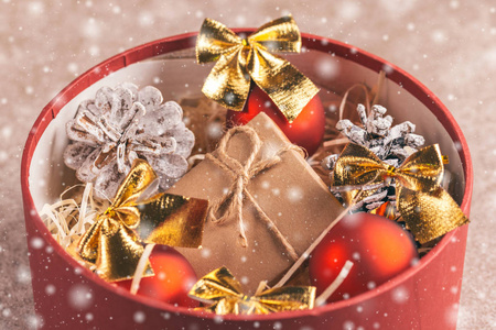 大的明亮的红色盒子，工艺包装的礼物和圣诞装饰内球弓圣诞树锥与雪效果。 水平视图。 复制空间
