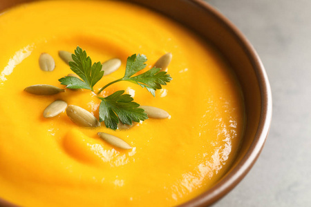 美味的南瓜奶油汤，种子和欧芹在碗特写。