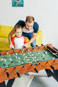笑着爸爸和儿子一起在家踢桌球图片