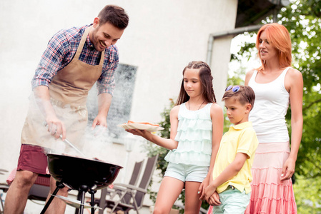 快乐的父亲为家人做饭，烧烤，夏季户外聚会