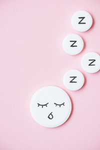 睡丸的顶部视图，有张脸和粉红色的z标记