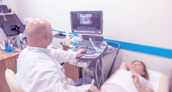 超声检查室不锐利的医学背景。 无重点医学背景的超声仪器在医疗室检查病人。 疾病的超声诊断
