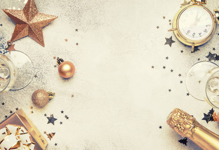 圣诞节或新年构图框架灰色背景与金色圣诞装饰，星星，雪花球，闹钟，礼品盒和香槟，顶部视图