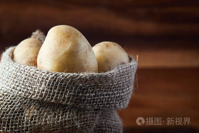 在木制背景上放一袋新鲜的生土豆复制空间