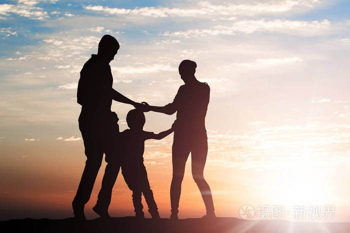 一家人在夕阳下手拉手围成一圈奔跑的剪影