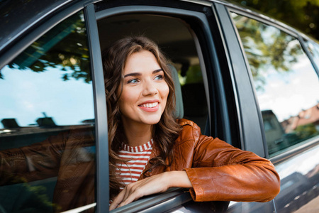 快乐的年轻女司机坐在车里等待乘客。