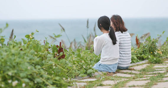 年轻妇女在海边聊天和坐着的后视图