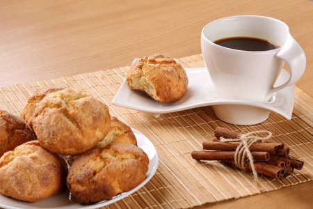 传统的保加利亚饼干叫做库拉比基咖啡杯，并在米色竹桌垫上绑上肉桂棒。 浅场深度选择性关注咖啡杯和咬饼干。 文本空间