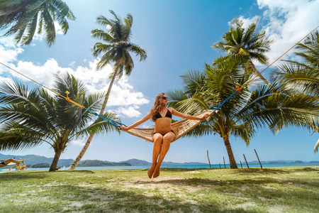女性在热带海滩的吊床上放松。 在菲律宾巴拉望岛享受海滩生活