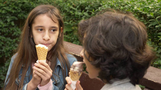 可爱的青少年, 男孩和女孩吃冰淇淋在公园和谈话